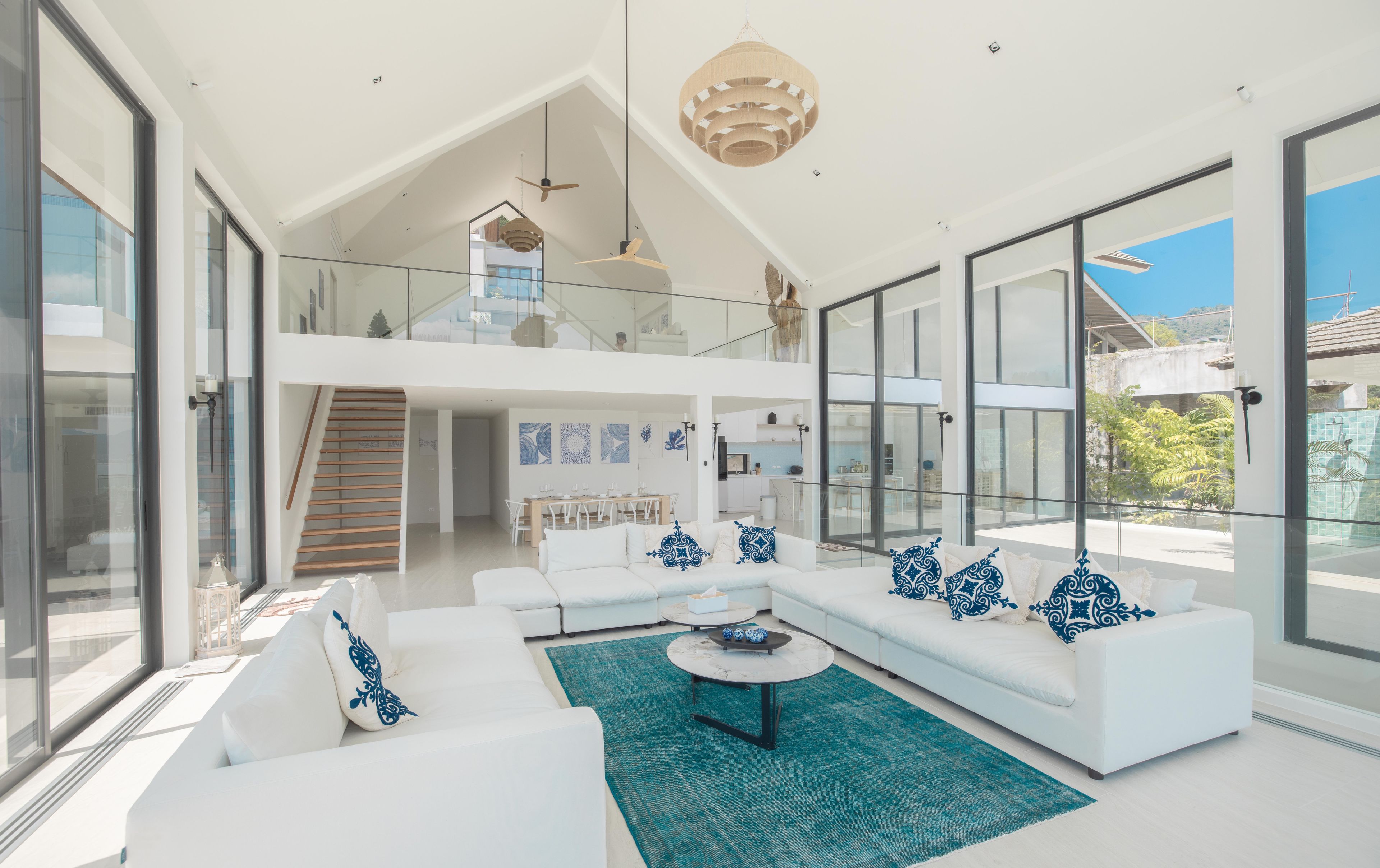 A modern living room with a white sofa set, a coffee table, and a staircase leading to an upper level.