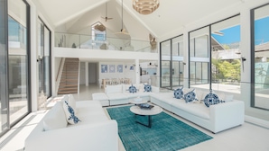 A modern living room with a white sofa set, a coffee table, and a staircase leading to an upper level. - Villa SARA (Kathu)