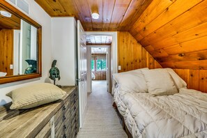 A bedroom with a wooden ceiling, a bed with white bedding, a nightstand, and a mirror. - Dock, Hot Tub & More! Lakefront Ortonville Oasis (Ortonville)