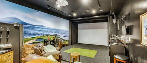 Ein Heimkino mit großer Leinwand, Sitzgelegenheiten und Projektor.