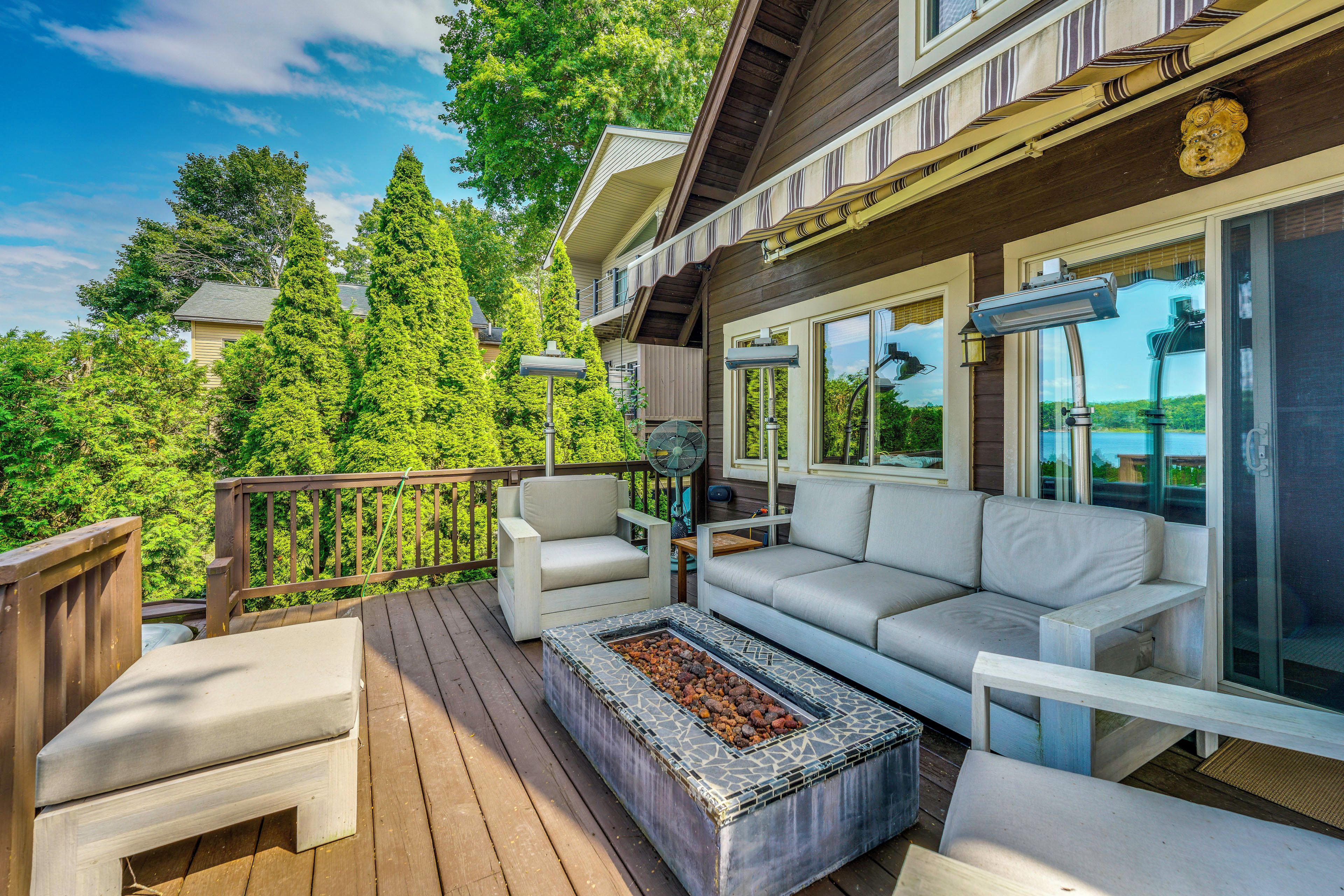 A deck with outdoor furniture, a fire pit, and a view of the surrounding greenery.