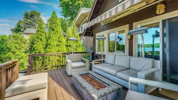 A deck with outdoor furniture, a fire pit, and a view of the surrounding greenery.