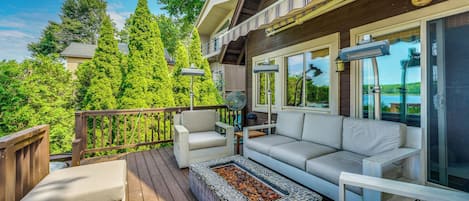Une terrasse dotée de mobilier d’extérieur, d’un foyer et offrant une vue sur la verdure environnante.
