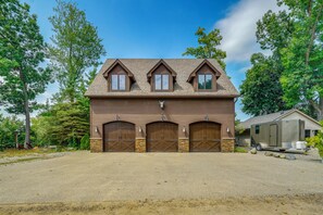 Une maison à deux étages, dotée d’un toit à pignon, de fondations en pierre et d’un garage à deux portes.