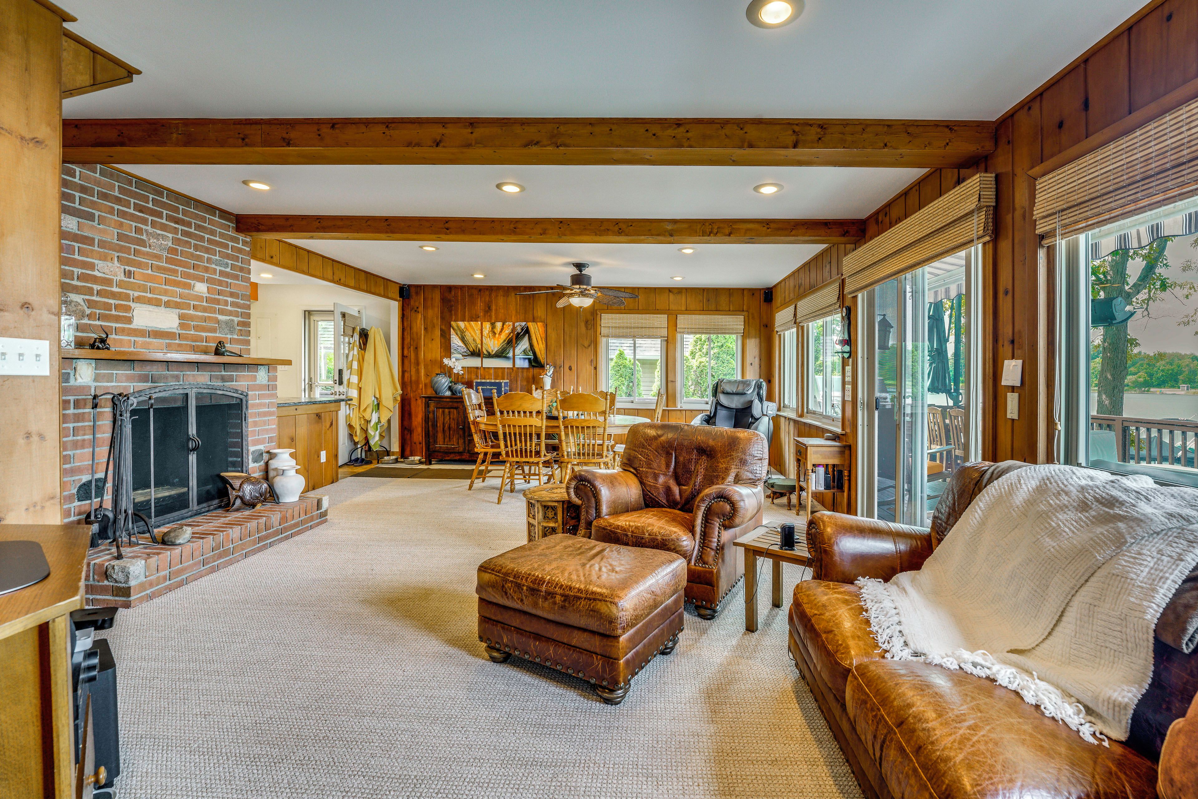 A spacious living room with a fireplace, leather furniture, and large windows.