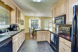 A kitchen with wooden cabinets, a black countertop, a built-in microwave, and a stove.