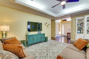 A living room with a sofa set, a television, and a decorative mirror on a teal cabinet.