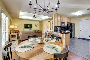 A dining area with a wooden table, chairs, and a ceiling fan.