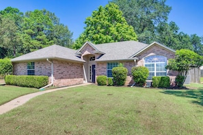 A two-story brick house with a covered front porch, a garage, and a well-maintained lawn.