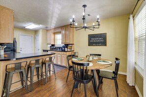 A kitchen with a dining area, wooden cabinets, a chandelier, and a sign on the wall.