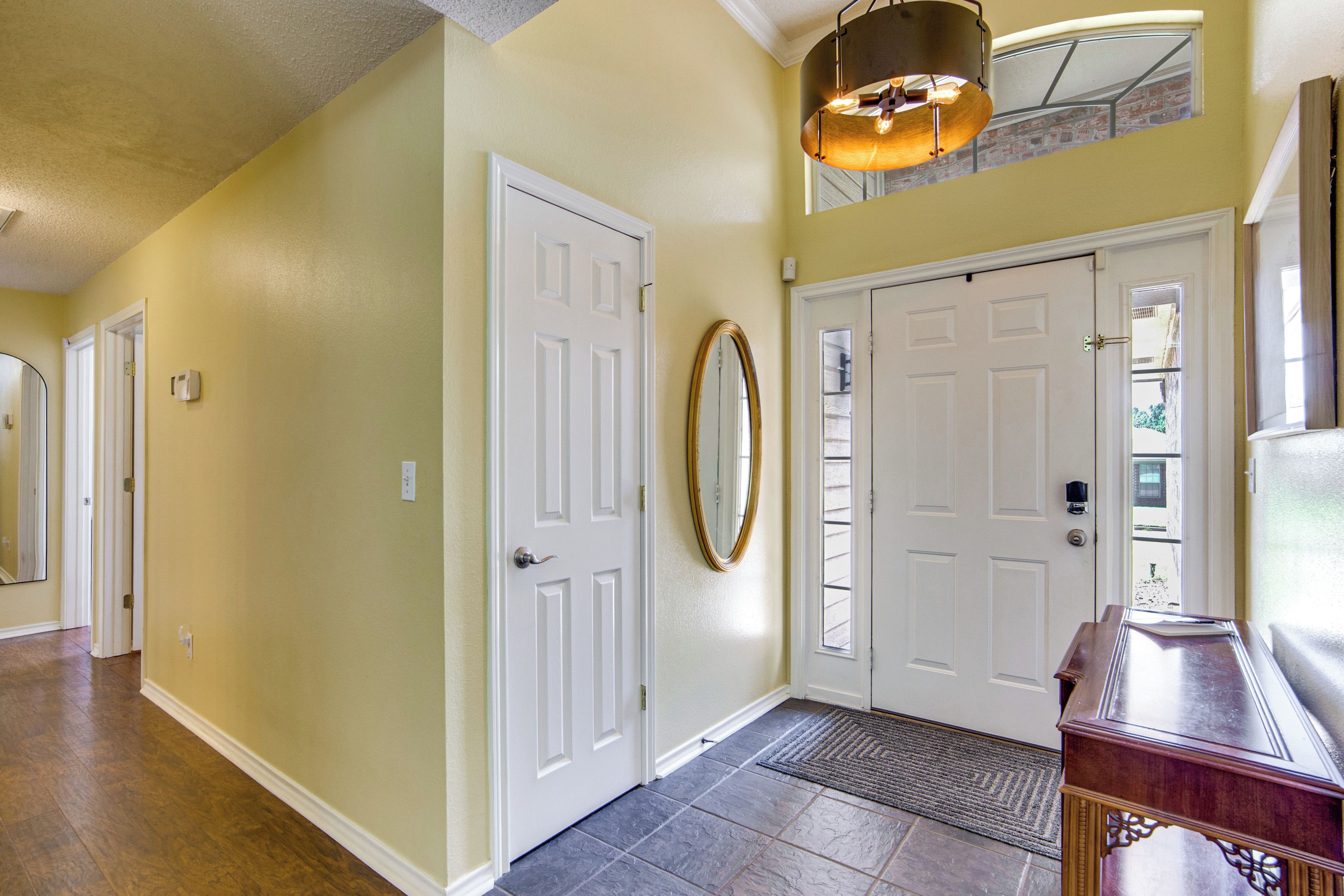 A hallway with two white doors, a mirror, and a light fixture.