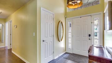 A hallway with two white doors, a mirror, and a light fixture.