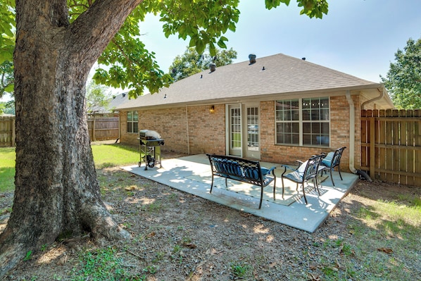 A residential backyard with a patio, a barbecue grill, and a wooden fence.
