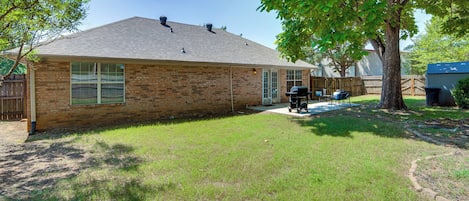 A residential house with a brick exterior, a covered patio, and a lawn.