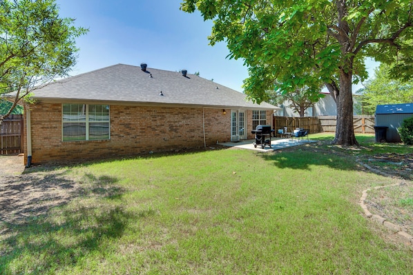 A residential house with a brick exterior, a covered patio, and a lawn.