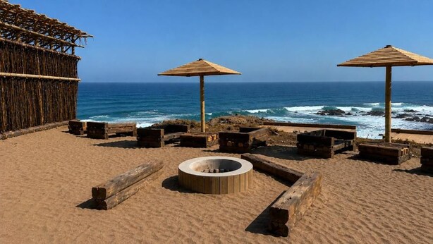 A beach with two wooden umbrellas, a fire pit, and a thatched structure. - La Ballenera Lodge (La Ballena)