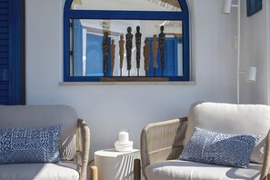 A room with two wicker chairs, a small round table, and a wall-mounted artwork. - Villa Akrotini with Sea view and Hot Tub (Kokkino Chorio)