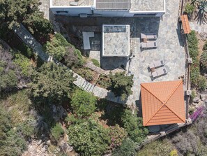 Vue aérienne d’une propriété dotée d’une terrasse en pierre, d’un espace salon extérieur et d’une végétation luxuriante.