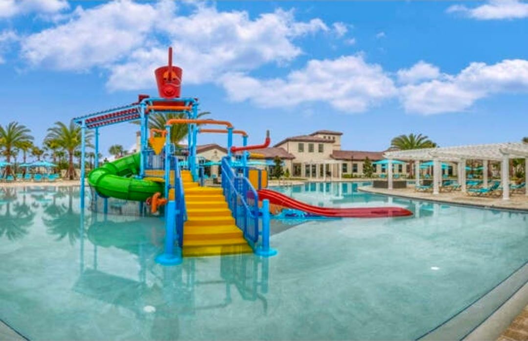 A water park with a multi-level play structure, a pool, and lounge areas.