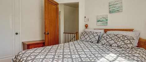 Um quarto com uma cama grande, uma porta de madeira, uma mesa de cabeceira e um quadro na parede.