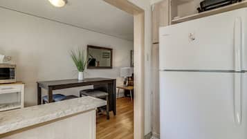 A compact kitchen with a refrigerator, a dining table with chairs, and a small countertop.