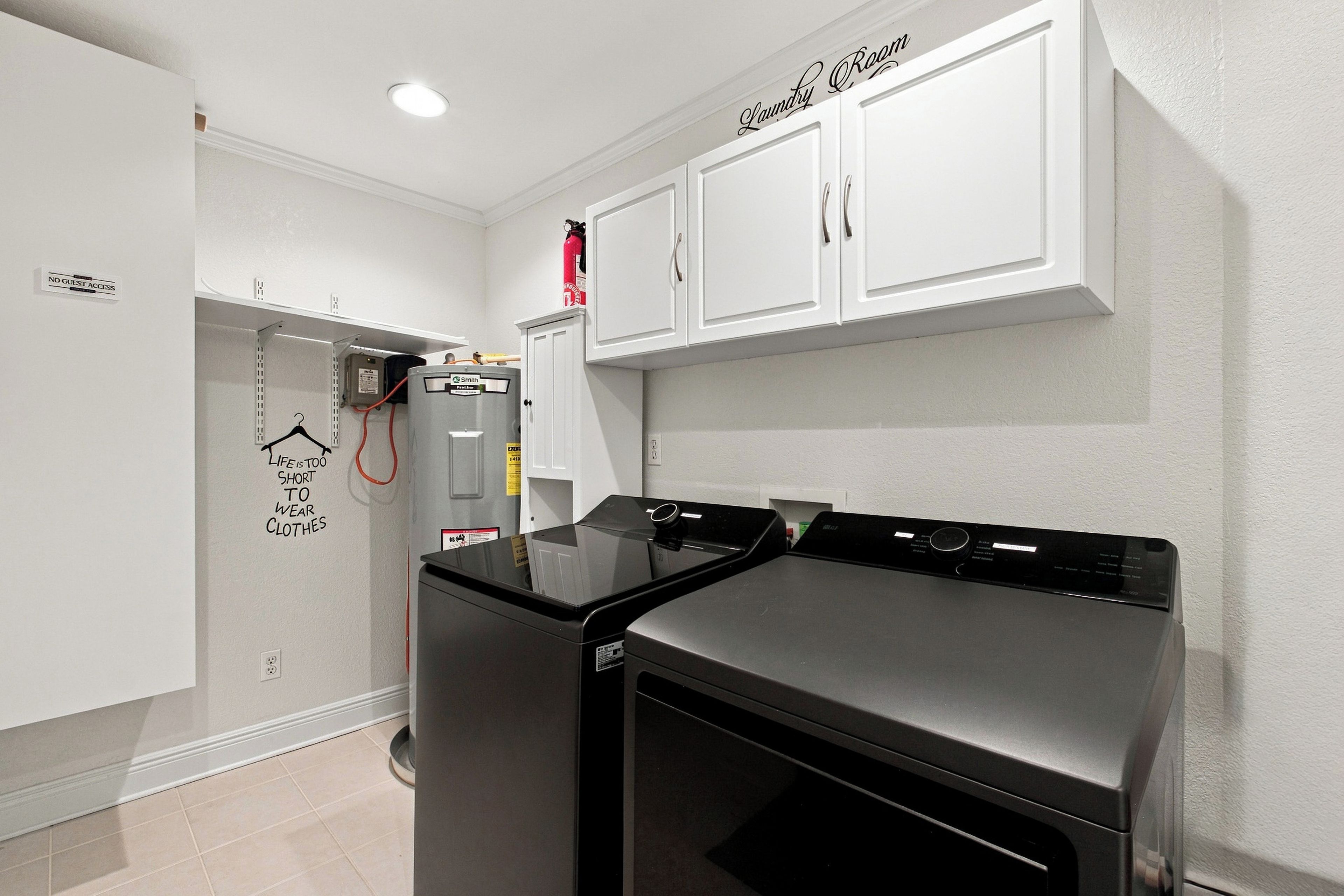 A laundry room with a dryer, a water heater, and a sign that reads 'Laundry Room.'