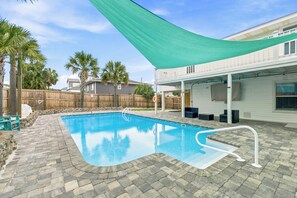 A swimming pool with a curved edge, surrounded by stone tiles. - Gulf View Home w/ Private Pool, Firepit, and Wraparound Porch | Sleeps 9 (Pensacola Beach)