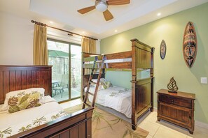 A room with a bunk bed, a ladder, a wooden cabinet, and a ceiling fan.