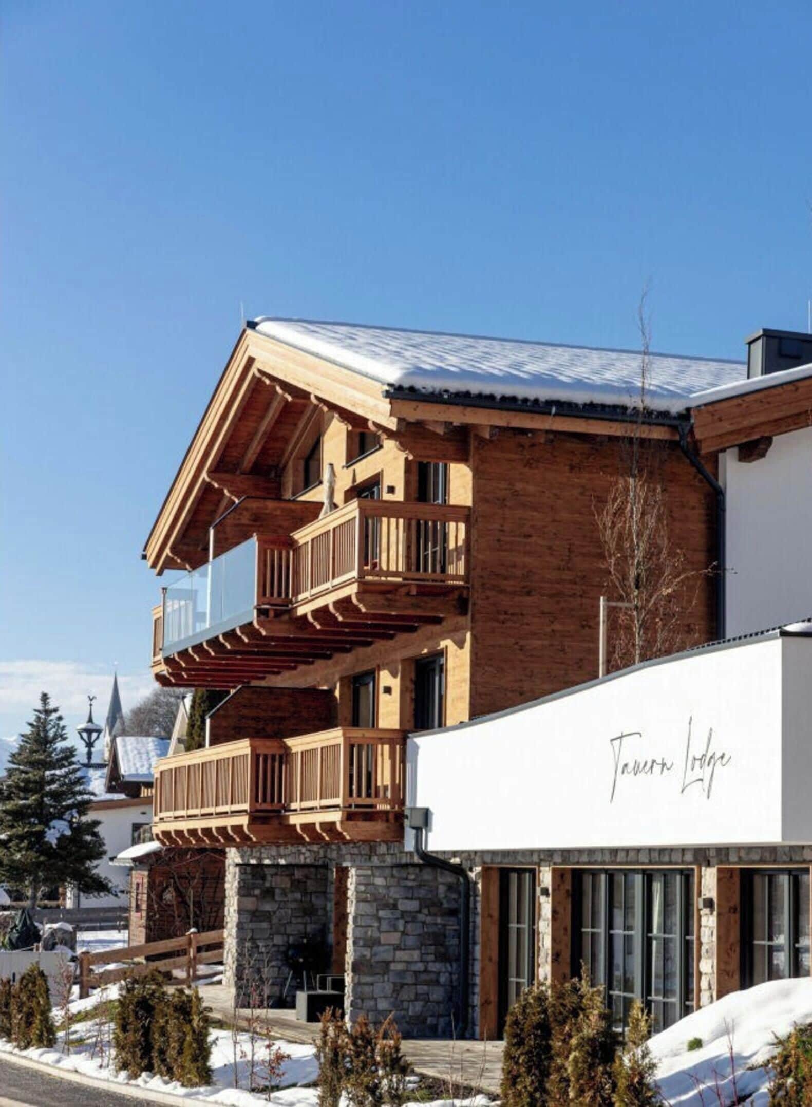 A multi-story building with wooden balconies and a stone base, named 'Tauron Lodge'.
