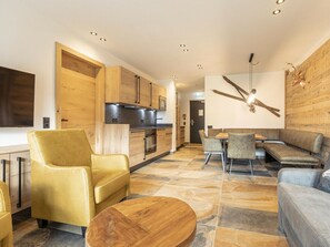 A modern kitchen with wooden cabinets and stainless steel appliances, a dining area with a wooden table and chairs, and a living area with a sofa and a coffee table. - Superior Holiday Apartment # 1C With Sauna (Uttendorf)