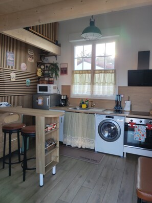 A compact kitchen with a washing machine, a microwave, and a coffee maker.