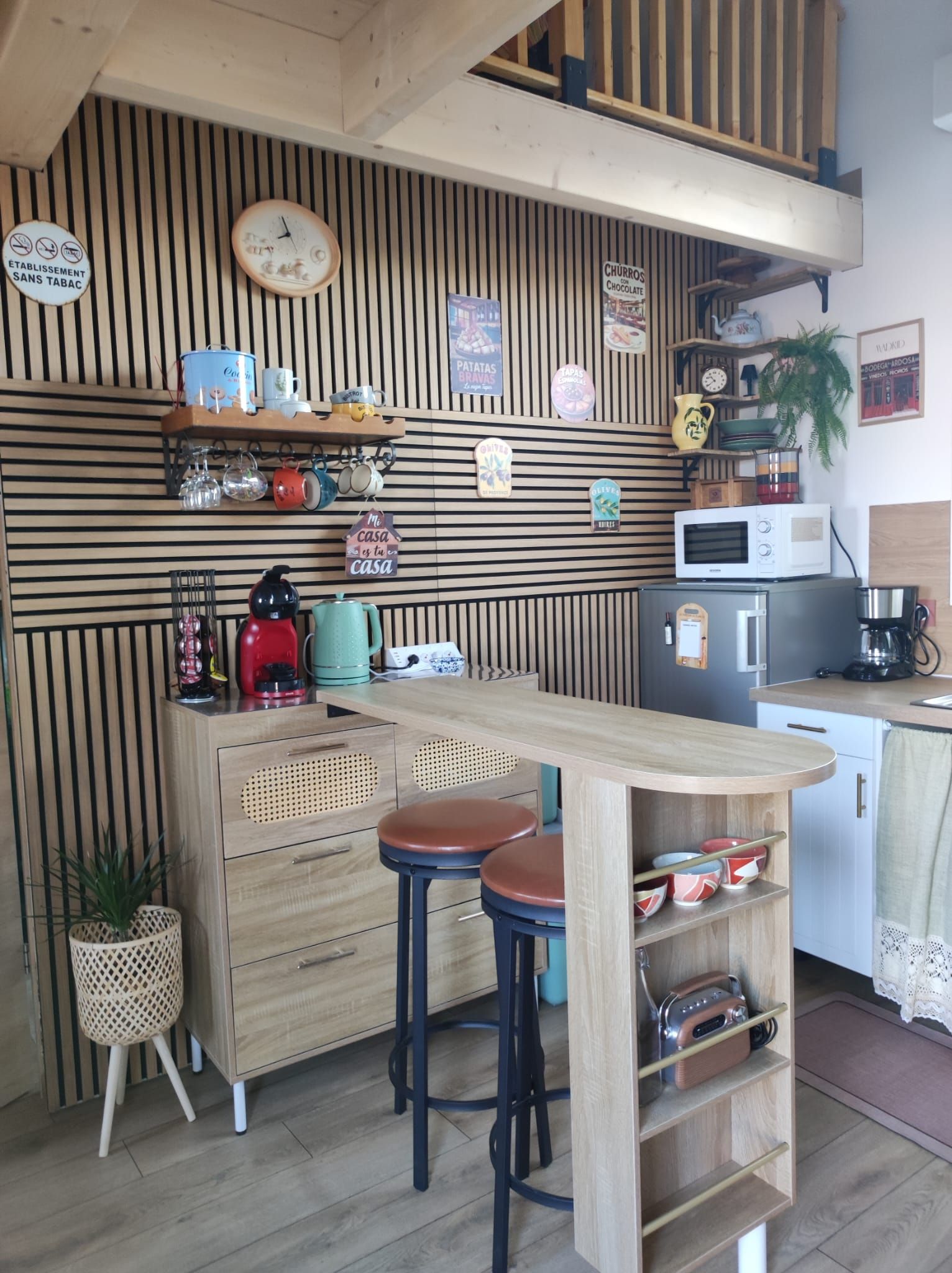 Una cocina con isla de madera, taburetes de bar, un microondas y varios electrodomésticos.