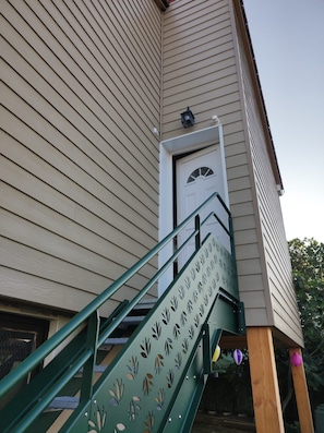 A staircase leading to a building entrance with a door and a small window above it. - Elena's Little House (Cholet)
