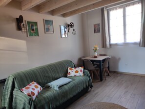 A cozy living room with a green sofa, a small table, and a window with curtains.