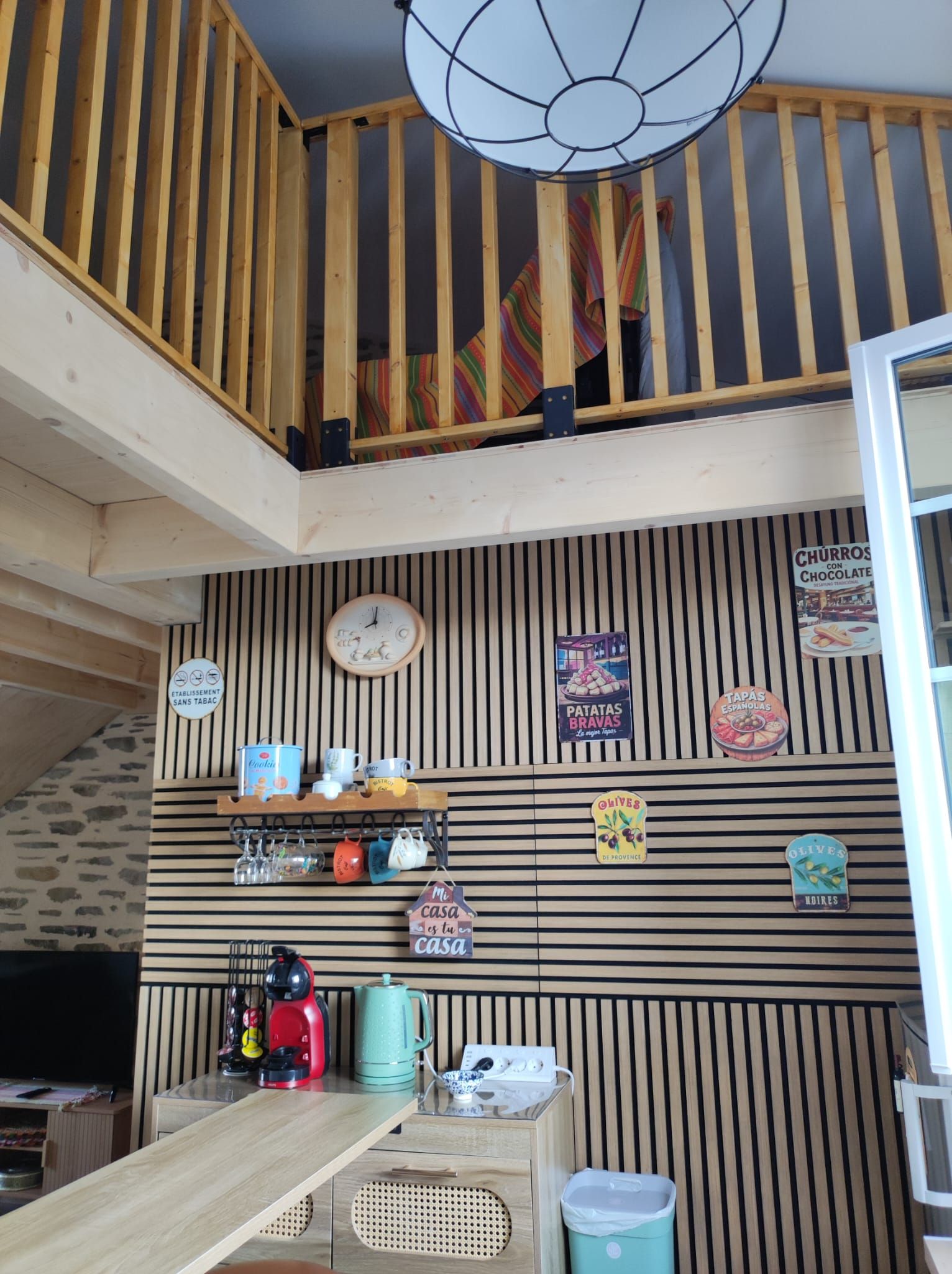 Un espace cuisine doté d’un plafond en bois, d’une horloge et de divers ustensiles et appareils de cuisine.
