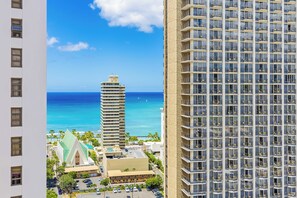 Un hôtel de grande hauteur doté de nombreux balcons, offrant une vue sur l’océan et disposant d’un parking avec plusieurs voitures.