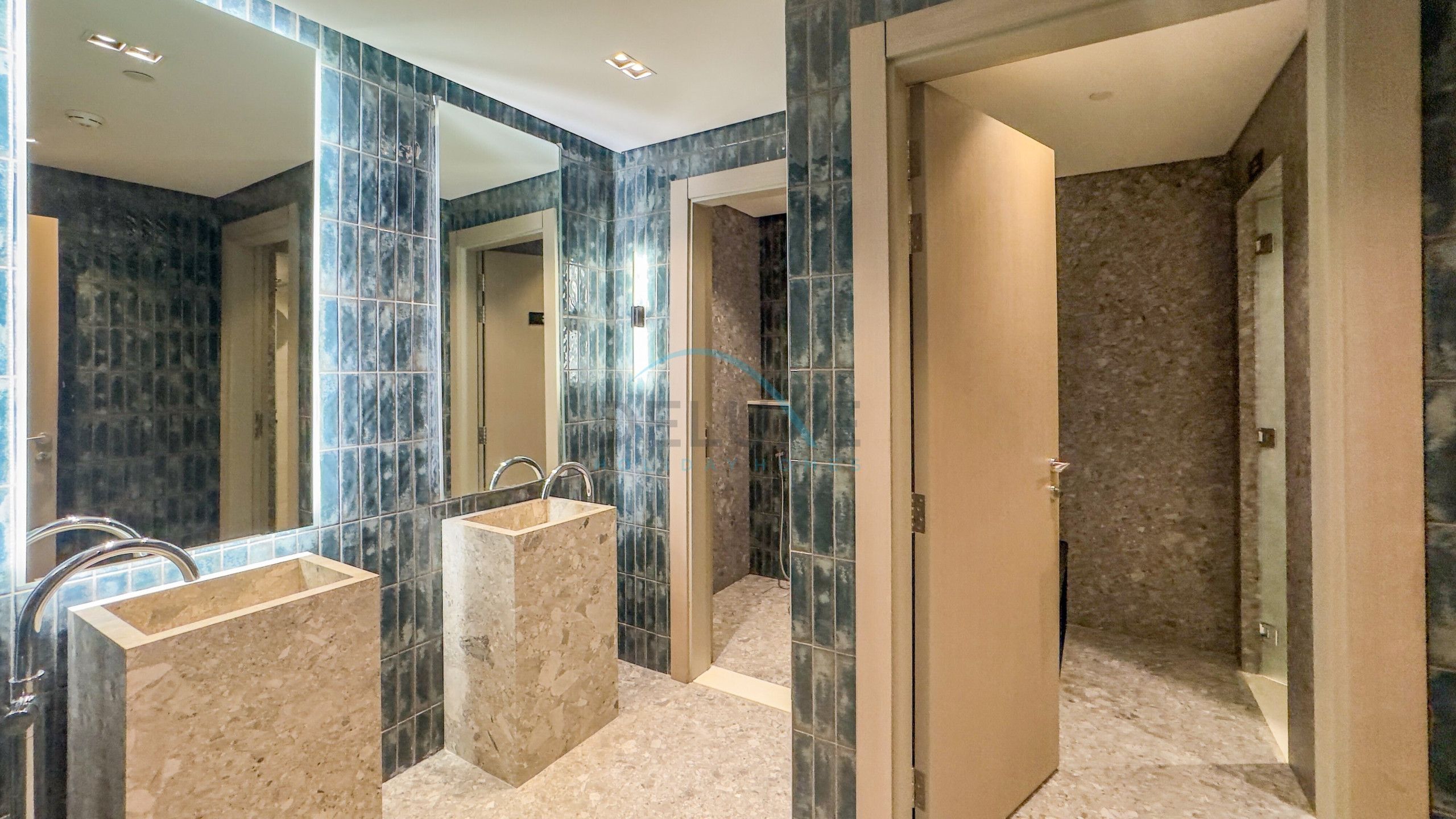 Une salle de bain moderne avec deux lavabos, une douche et un grand miroir.