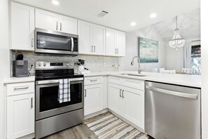 A modern kitchen with stainless steel appliances, white cabinetry, and a striped rug. - NEW Listing*Book 3 Nights Get 1 Free/See Description*Golf Cart*Beach/Pool Access (Miramar Beach)