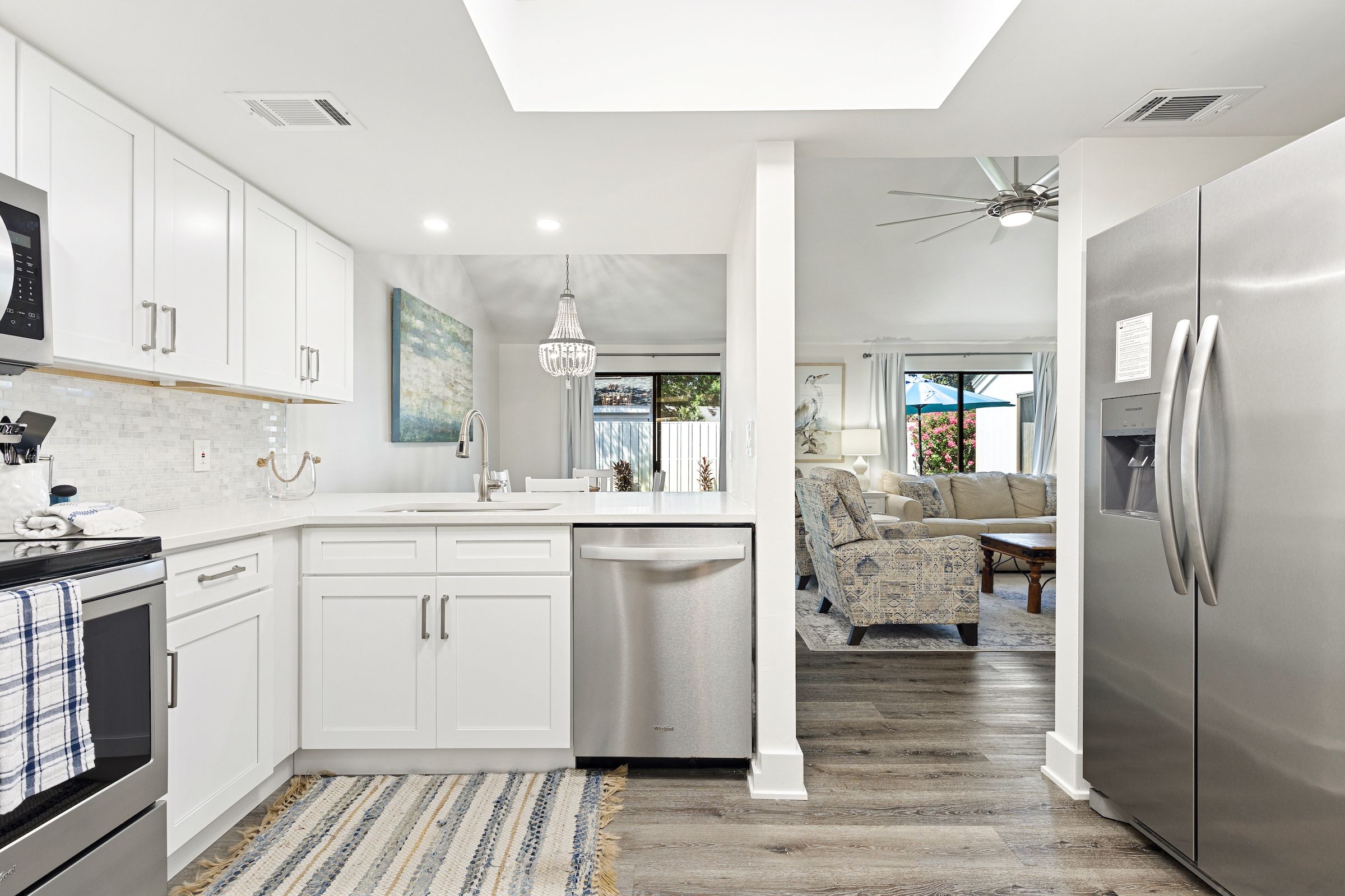 A modern kitchen with white cabinetry, a dishwasher, and a stainless steel refrigerator.