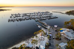 A marina with multiple docks and boats, a sandy beach area with seating, and a clear view of the water. - Book 3 Nights, Get 1 Free (See Description) | Renovated, Golf Cart, Beach & Pool (Miramar Beach)