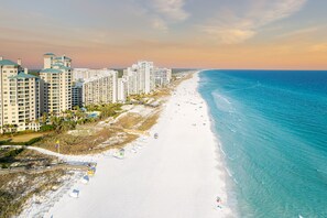 A coastal hotel with multiple high-rise buildings, a sandy beach, and a clear view of the ocean. - Book 3 Nights, Get 1 Free (See Description) | Renovated, Golf Cart, Beach & Pool (Miramar Beach)