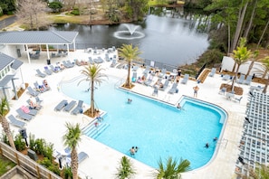 A swimming pool with lounge chairs and palm trees, surrounded by a building and a body of water. - Book 3 Nights, Get 1 Free (See Description) | Renovated, Golf Cart, Beach & Pool (Miramar Beach)