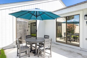 An outdoor patio with a round table and four chairs, a blue umbrella, and a stone wall. - NEW Listing*Book 3 Nights Get 1 Free/See Description*Golf Cart*Beach/Pool Access (Miramar Beach)