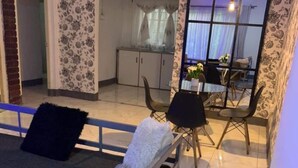 Ein Zimmer mit einem Bett, einem Essbereich mit Stühlen und einem Tisch sowie einer Küche im Hintergrund.