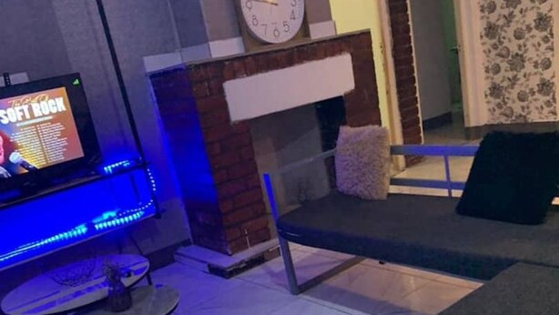 Ein Wohnzimmer mit einer Couch, einem Fernseher, einer Uhr und einem Kamin.