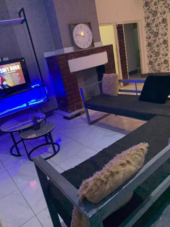 Una sala de estar con un sofá, un televisor, un reloj y una chimenea.