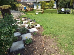 Un jardín con sendero empedrado, bancos y una mesa de picnic.