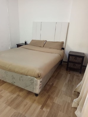 Un dormitorio con cama, mesita de noche y velador.