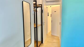 A hallway with a mirrored wardrobe, a wooden floor, and an air conditioning unit.