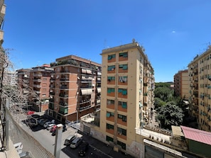 A multi-story residential building with balconies, a parking area, and a clear blue sky. - Luciano Queen's Guest House (Rome)